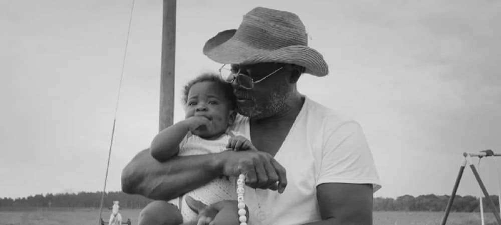 A Black farmer holds a baby in Seeds, the Full Frame Documentary Film Festival Grand Jury Award winner