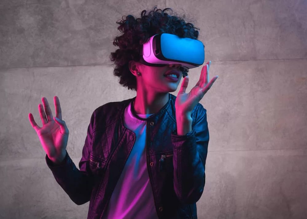 A young woman with curly hair wears a virtual reality headset. She holds her hands out as if interacting with an environment. The question remains, how virtual reality transforms the moviegoing experience