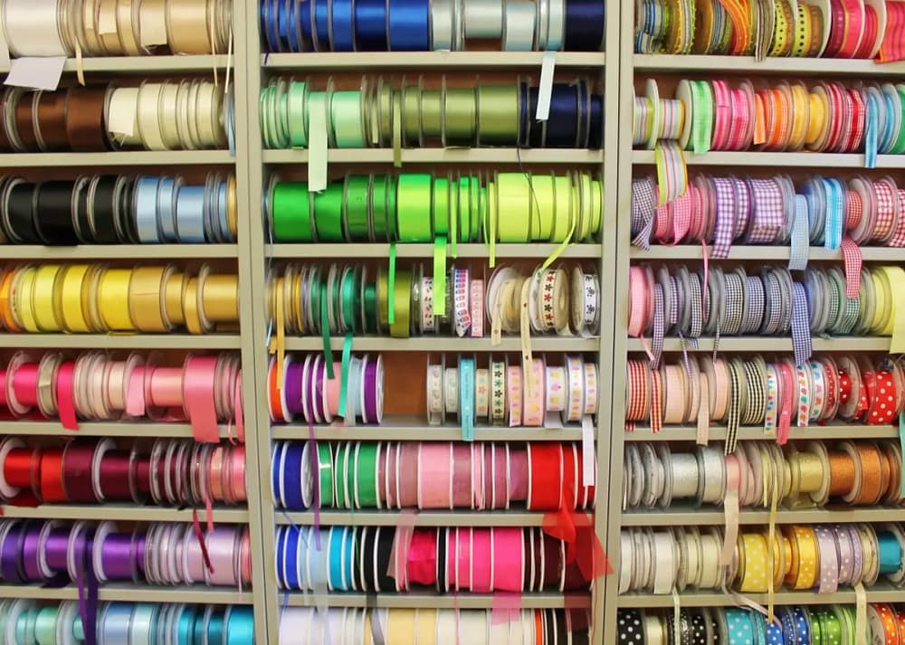 Several tens of spools of ribbon are organized on a wall. The ribbon is in order by color and pattern. This is how to store and organize your crafting ribbon