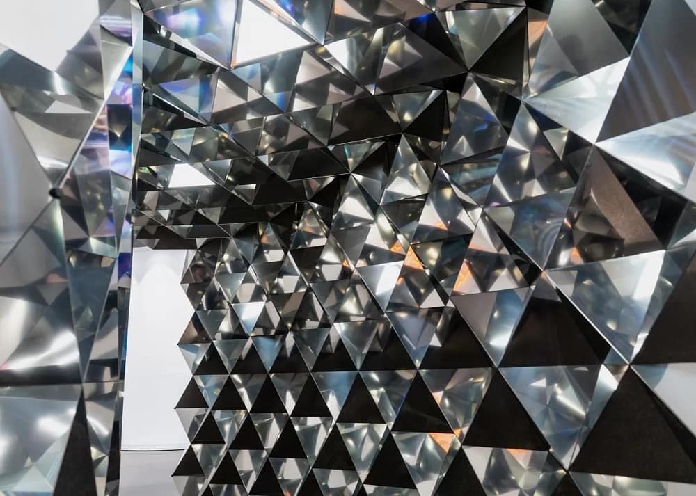 Designing immersive exhibitions with reflective materials: abstract mirrored triangular panels in immersive exhibition design reflecting light in a prismatic pattern