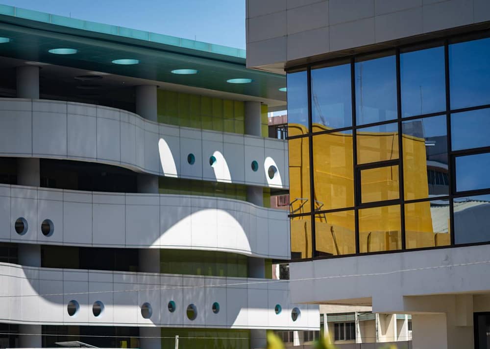 Small Architectural details that lend a space prestige are showcased in this contemporary building with white curved walkways, circular openings, and mirrored glass reflecting warm yellow walls.