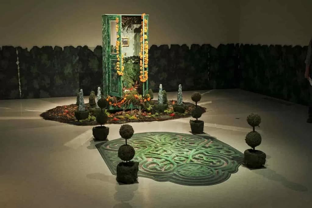 Amalia Mesa-Bains: Private Landscapes and Public Territories, 1998-2011/2018; mixed media installation including a painted and mirrored armoire, found objects, moss, dried flowers, faux topiaries, family photographs, miniature jeweled trees, painted wooden hedges; 120 x 240 x 300 in. 