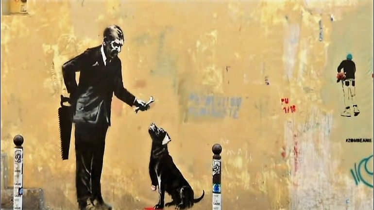 Image: In one of the new Banksy works in Paris, a man hiding a saw behind his back offers a three-legged dog a bone.