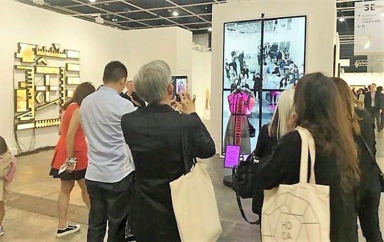 Image: Guests at the de Sarthe booth during Art Basel Hong Kong interact with Wang Xin installation titled Unknown Artists Promotion Service Walking Promotions by Unknown Artists Agency