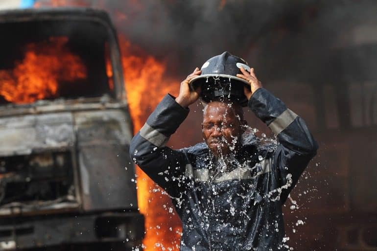 Image- Fireman, fire truck shows a fireman dowsing himself with water in this documentary photography by Akintunde Akinleye