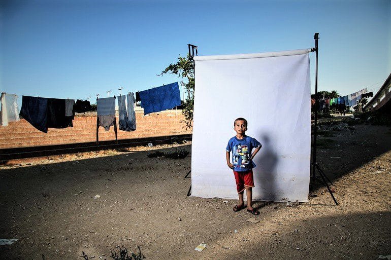 Image: Photograph of a Boy wearing a red polo tee shirt with Mickey Mouse prints in front of a white background is one of the photographs by Iranian photographer Amir Kabir Jabbari highlighting the lives children